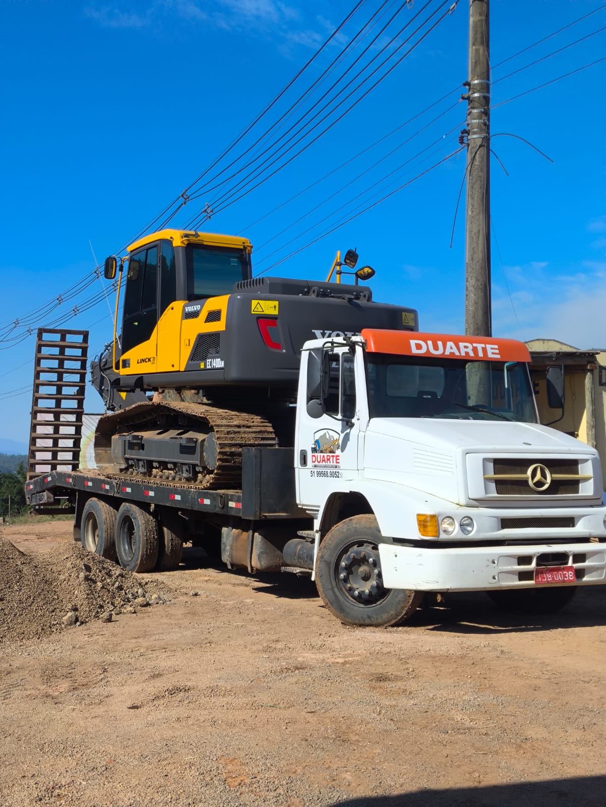 Caminhão da Duarte Terraplanagem transportando retroescavadeira JCB